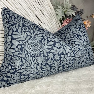 May include: Two blue throw pillows with a white floral pattern. The pillows are made of a textured fabric and have a subtle sheen.