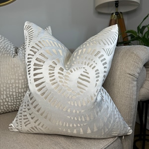 May include: Two decorative throw pillows with a geometric pattern. The pillow on the left is a light gray with a white dot pattern. The pillow on the right is a light gray with a white swirl pattern.