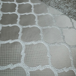 May include: A close-up of a grey fabric with a white geometric pattern. The fabric has a subtle texture and a soft, luxurious feel.
