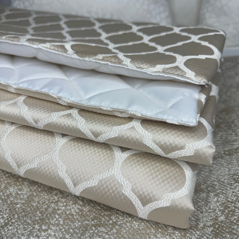 May include: A stack of four beige fabric squares with a white geometric pattern. The fabric is soft and luxurious, and the pattern is subtle and elegant.