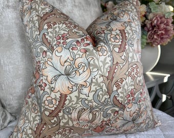 May include: A decorative throw pillow with a floral pattern. The pillow features a cream background with a repeating design of stylized flowers and foliage in shades of peach, brown, and blue. The pillow is square and appears to be made of a soft fabric.