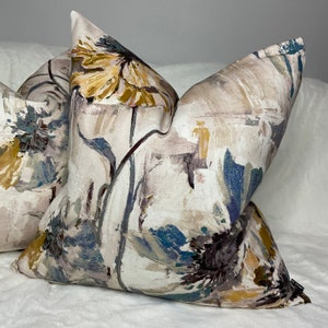 May include: Two decorative throw pillows with a floral pattern in shades of blue, yellow, and brown on a white background.