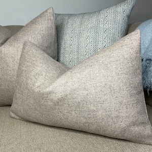 May include: Two gray throw pillows with a patterned blue pillow in the background. The pillows are made of a soft, textured fabric.