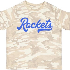 May include: A beige camouflage t-shirt with a blue "Rockets" graphic.