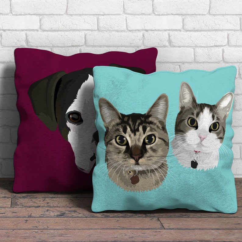 May include: Two decorative throw pillows with a dog and cat design. The pillow on the left is a dark red color with a black and white dog face. The pillow on the right is a light blue color with a tabby cat face and a white and gray cat face.