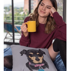 May include: A gray throw pillow with a custom illustration of a black and brown dog with a pink collar and a blue tag. The dog is looking directly at the camera.