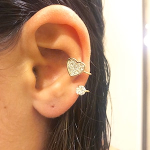 Peut inclure: Une paire de boucles d'oreilles en or avec des embellissements en cristal transparent. L'une des boucles est en forme de cœur et l'autre est un cercle rond.