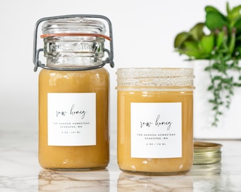 May include: Two glass jars of raw honey with white labels that read "raw honey" and "The Hanson Homestead, Shakopee, MN 4 oz | 118 ml".