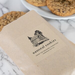 May include: A brown paper bag with a label that says "oatmeal cookies from the negard homestead homemade for you". The label has a black and white illustration of a cabin with trees.