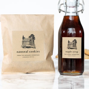 May include: A brown paper bag with a label that reads "oatmeal cookies from the McGard Homestead homemade for you". A glass bottle with a brown label that reads "maple syrup the Lopez Homestead made in Maine".