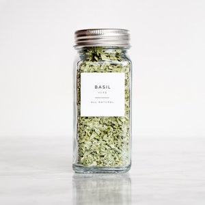 May include: A glass jar filled with dried basil leaves. The jar has a silver lid and a white label that reads "BASIL HERB ALL NATURAL".