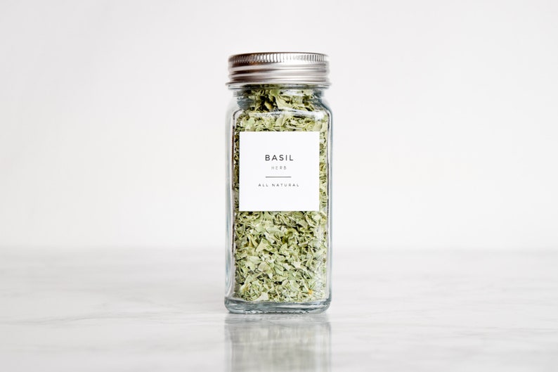 May include: A glass jar filled with dried basil leaves. The jar has a silver lid and a white label that reads "BASIL HERB ALL NATURAL".