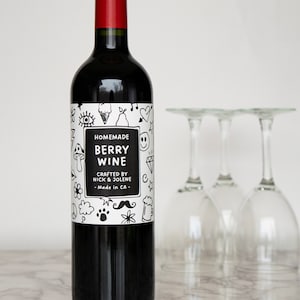 May include: A bottle of homemade berry wine with a white label featuring black doodle illustrations and the text "Homemade Berry Wine Crafted by Nick & Jolene - Made in CA - "