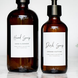 May include: Two amber glass bottles with black pumps and labels. One reads "Hand Soap" and the other "Dish Soap". The labels also include "Hand Cleanser" and "Grease-Cutting". The bottles are part of the "Home & Bath Collection".