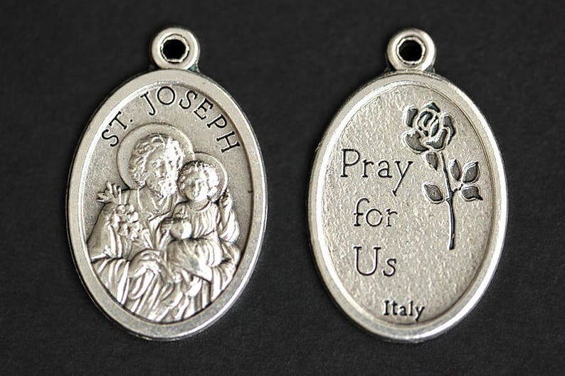 May include: Silver oval pendant with a depiction of Saint Joseph holding the baby Jesus. The back of the pendant reads "Pray for Us Italy".