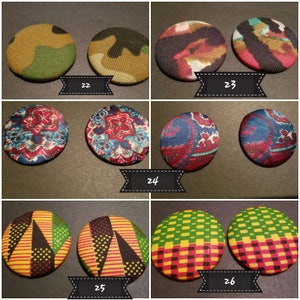 May include: Set of 10 fabric covered buttons with various patterns. The buttons are round and have a diameter of approximately 2 inches. The patterns include camouflage, paisley, floral, and geometric designs. The buttons are in various colors, including green, red, blue, yellow, and black.