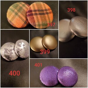 May include: Assortment of fabric covered buttons in various colors and patterns. The buttons are arranged in pairs and labeled with numbers. The buttons are approximately 1 inch in diameter.
