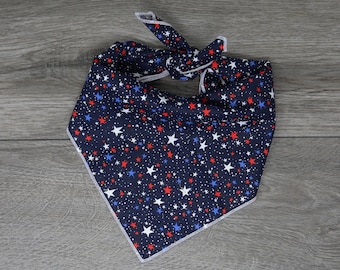 Puede incluir: Un pañuelo azul marino con estrellas blancas y rojas. El pañuelo tiene un borde blanco y está atado en un nudo.