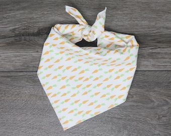 May include: White bandana with a pattern of orange carrots on a white background. The bandana is tied in a knot at the top.