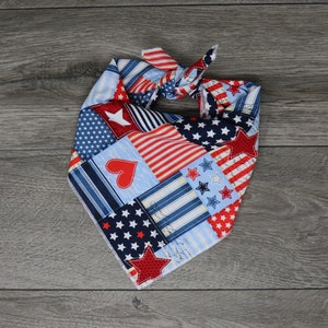 May include: A red, white, and blue bandana with a patchwork design featuring stars and hearts. The bandana is tied in a knot.