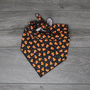 May include: Black bandana with a pattern of orange and white candy corn on a black background.