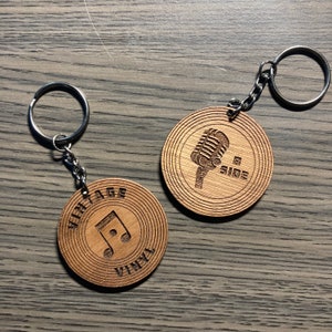 May include: Two wooden keychains with silver key rings. One keychain features a musical note and the words "VINTAGE VINYL". The other keychain has a microphone design and the words "B SIDE".