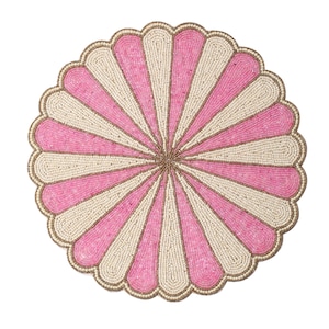 May include: A round beaded placemat with a scalloped edge. The design features alternating pink and cream-colored beaded stripes radiating from the center. A thin, gold-colored border outlines the edge of the placemat. The placemat is on a white background.