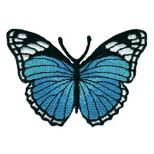 Könnte beinhalten: Ein blauer Schmetterling mit schwarzen Umrissen und weißen Akzenten. Der Schmetterling ist gestickt und hat ein detailliertes Design.