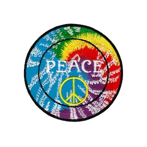 Puede incluir: Un parche redondo de tie-dye colorido con un símbolo de paz y la palabra "PEACE" en letras blancas.