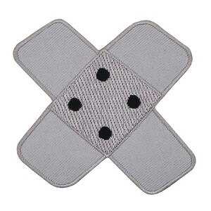 Puede incluir: Un parche de tela gris en forma de cruz con cuatro puntos negros en el centro. El parche es un diseño simple que se asemeja a una venda.