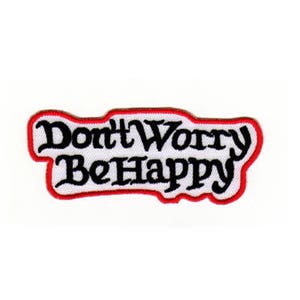 Op de afbeelding: Witte geborduurde patch met rode stiksels. De patch zegt "Don't Worry Be Happy" in een zwart cursief schrift.