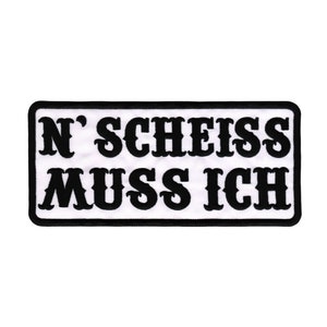 Könnte beinhalten: Schwarz-weiß gestickter Aufnäher mit dem Text "N'SCHEISS MUSS ICH".