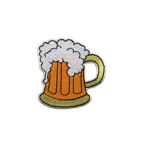 Könnte beinhalten: Gestickter Aufnäher mit einem Cartoon-Bierkrug, der mit weißem Schaum überläuft. Der Krug ist orange mit vertikalen Linien, einem grünen Boden und einem grünen Henkel. Geeignet für das Aufnähen auf Kleidung oder Accessoires.
