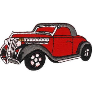 Könnte beinhalten: Rotes Oldtimer-Auto mit schwarzem Kühlergrill und weißen Akzenten. Das Auto hat ein schwarzes Verdeck und weiße Räder.
