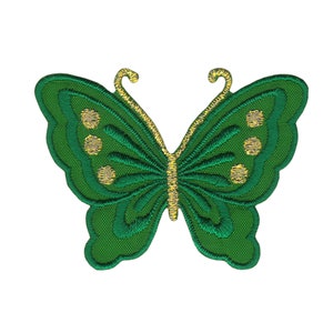 Könnte beinhalten: Grüner gestickter Schmetterlings-Patch mit goldenen Akzenten. Der Schmetterling hat ein detailliertes Design mit einem gewellten Rand.