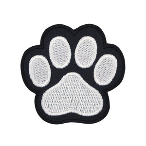 Könnte beinhalten: Schwarzer Pfotenabdruck-Patch mit weißen Stickdetails. Der Patch ist aus Stoff und hat einen genähten Rand.