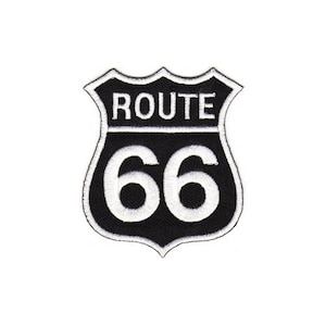 Könnte beinhalten: Schwarz-weiß gestickter Patch in Schildform. Der Patch trägt den Text "ROUTE 66" in Weiß.
