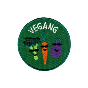 Könnte beinhalten: Grüner gestickter Aufnäher mit dem Wort "VEGAN" in weißen Buchstaben. Der Aufnäher zeigt einen Cartoon-Brokkoli, eine Karotte und eine Aubergine mit Sonnenbrillen.