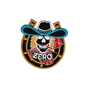 Könnte beinhalten: Gestickter Aufnäher mit einem Totenkopf, der einen Cowboyhut trägt und eine Zigarette raucht, in einem Hufeisen mit dem Wort "ZERO" darunter. Der Totenkopf trägt einen rot-weißen Schal und das Hufeisen ist golden mit schwarzem Hintergrund.