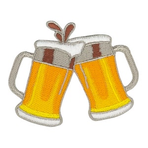 Könnte beinhalten: Zwei graue Keramik-Bierkrüge mit gelbem Bier und weißem Schaum, die aneinanderstoßen. Die Krüge haben braune Henkel und einen braunen Streifen am oberen Rand.