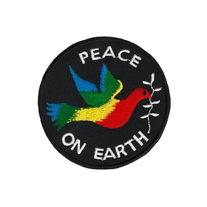 Könnte beinhalten: Ein schwarzer runder Patch mit weißer Stickerei, auf dem "PEACE ON EARTH" steht. In der Mitte ist eine bunte Taube mit einem Olivenzweig im Schnabel gestickt.