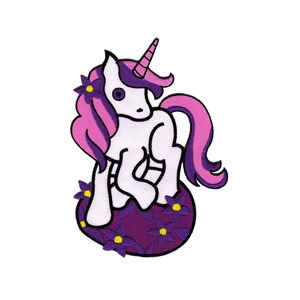 May include: A white unicorn with a pink and purple mane and tail sits on a bed of purple flowers with yellow centres. The unicorn has a purple horn and large, black eyes.