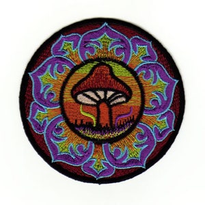 Op de afbeelding: Gestikt patch met een psychedelisch paddenstoelontwerp. De paddenstoel is rood en wit met een groene en oranje achtergrond. Het patch is omringd door een paarse en groene mandala.