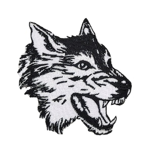 Op de afbeelding: Zwart-witte geborduurde patch van een wolfskop met zijn bek open en tanden zichtbaar.