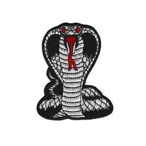 Peut inclure: Patch brodé noir et blanc d'un cobra aux yeux rouges et à la langue rouge. Le cobra est enroulé sur lui-même, la tête levée.