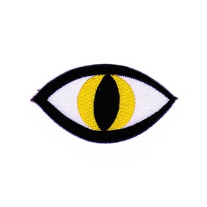 Könnte beinhalten: Schwarzer und gelber gestickter Augen-Patch mit weißem Zentrum.