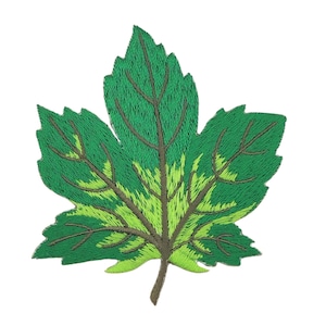 Op de afbeelding: Geborduurde bladpatch in groen- en geeltinten. De patch heeft gedetailleerde stiksels, die de nerven en randen van het blad laten zien. Het blad heeft een bruine steel en is geplaatst tegen een witte achtergrond.
