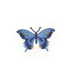 Peut inclure: Patch brodé de papillon bleu avec des accents dorés. Le papillon a un corps bleu foncé et des ailes bleu clair avec des taches dorées.