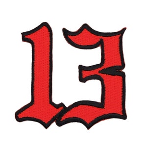 Könnte beinhalten: Roter gestickter Bügel-Patch mit der Zahl 13 in gotischer Schrift.