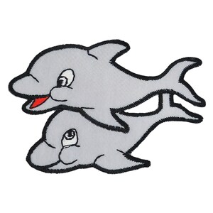 Puede incluir: Un parche bordado gris de dos delfines, uno más grande que el otro, nadando uno al lado del otro. Los delfines tienen contornos negros y bocas rojas.